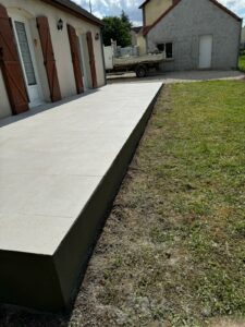 Terrasse extérieure surélevée en béton et carrelage blanc